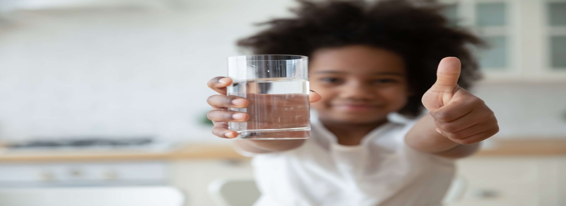 A child holding a glass of water, showcasing the benefits of water softener systems.