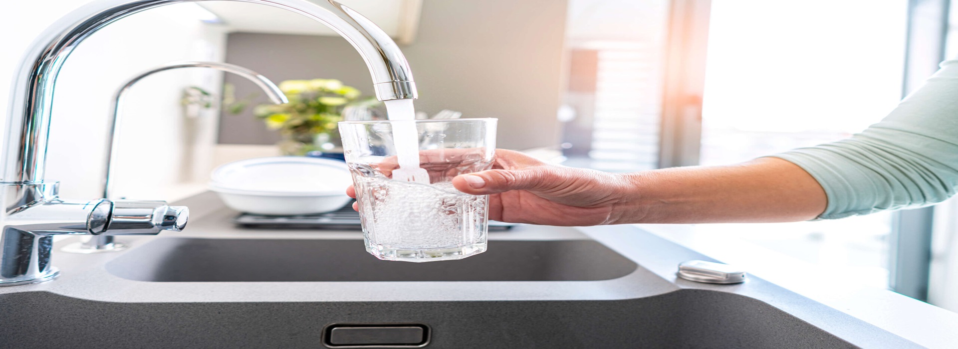 Filling a glass with water from a kitchen faucet connected to a water softener system.